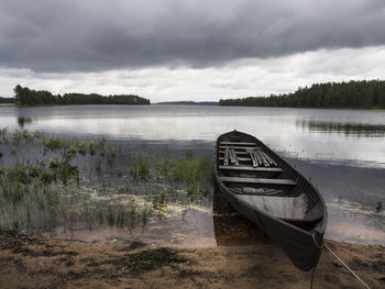 Boats in lake against cloudy sky