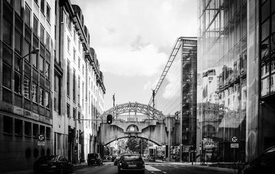 Cars on city street by buildings against sky