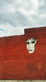 Mural on wall against cloudy sky