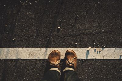 Low section of man wearing brown shoes standing on road