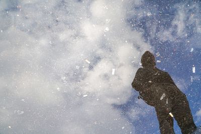 Low angle street view of a man silhouette standing in a blue cloudy sky reflection in a urban flake.