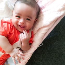 High angle portrait of smiling baby lying on bed at home