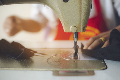 Midsection of tailor using sewing machine