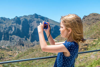 Midsection of woman photographing against mountain