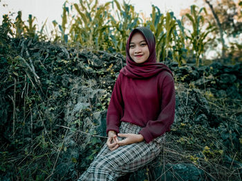 Full length of smiling young woman sitting on land