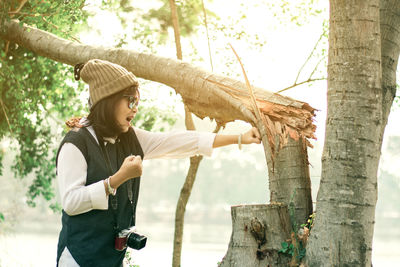 Side view of woman punching tree trunk