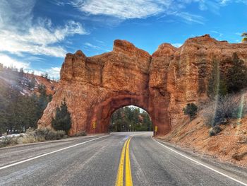 Road leading towards rock formation against sky