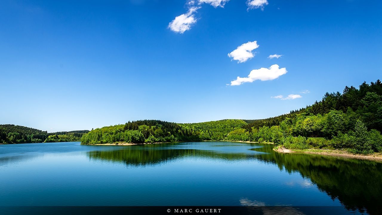 water, blue, tranquil scene, reflection, tranquility, scenics, lake, tree, beauty in nature, waterfront, nature, sky, standing water, idyllic, clear sky, mountain, calm, copy space, day, non-urban scene