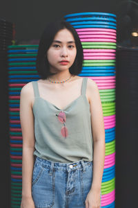 Portrait of young woman standing against multi colored objects