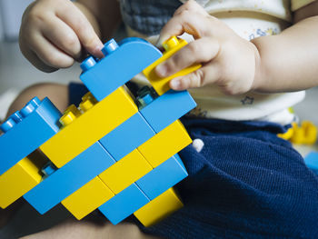 Baby playing with blue and yellow lego bricks