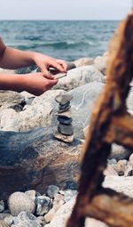 Cropped hands of woman stacking rocks at beach