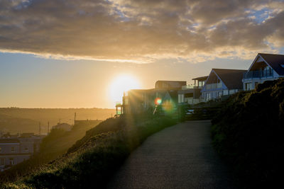 Footpath amidst buildings against sky during sunset