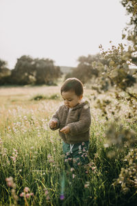 Boy standing by plant on field