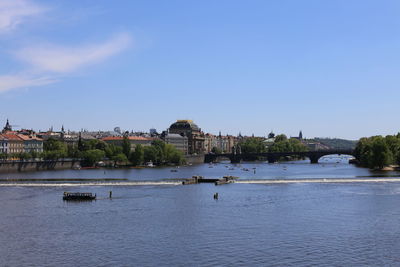 View of buildings by river against sky