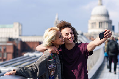 Young man taking selfie with friend in city