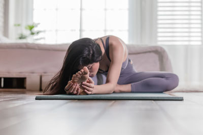 Young woman stretching while practicing yoga at home