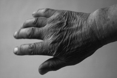 Close-up of man with wrinkled hand against gray background