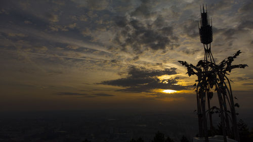 Silhouette statue against dramatic sky during sunset