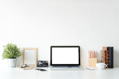 Laptop with office supply on desk against gray background