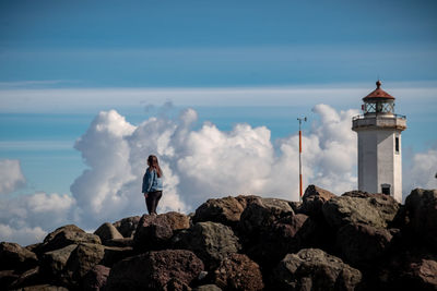 People standing on rock by sea against sky