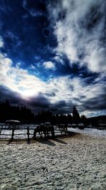 Silhouette trees on snow covered land against sky