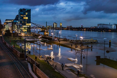 Illuminated pier over river against sky at dusk