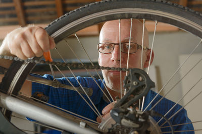 Portrait of mature man repairing bicycle in garage