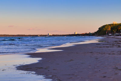 Scenic view of beach against clear sky during sunset