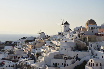 Residential buildings by sea against clear sky