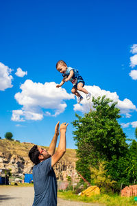 Low angle view of friends standing on tree against blue sky