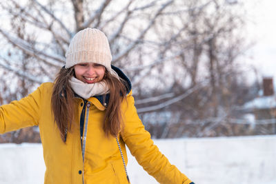 Portrait of happy young woman in yellow jacket skating at the rink