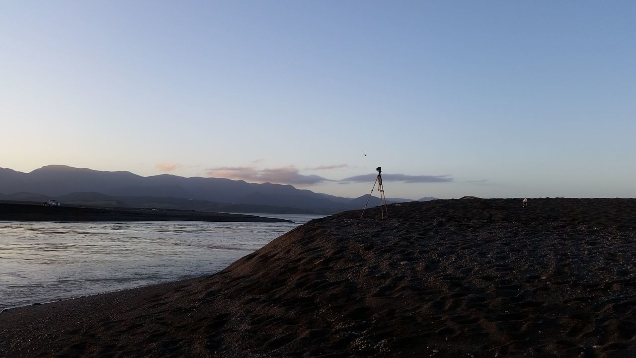 tranquil scene, tranquility, water, sea, copy space, scenics, clear sky, beauty in nature, nature, beach, sky, silhouette, mountain, idyllic, shore, remote, standing, non-urban scene