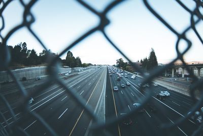 Railroad tracks in city seen through chainlink fence