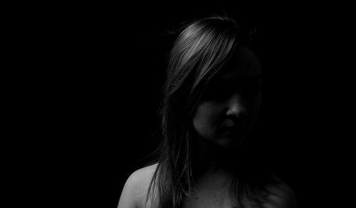 Close-up portrait of a young woman over black background