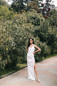 Full length of woman standing by plants against trees