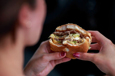 Close-up of hands holding hamburger outdoors