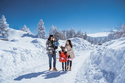 Rear view of people skiing on snow covered landscape