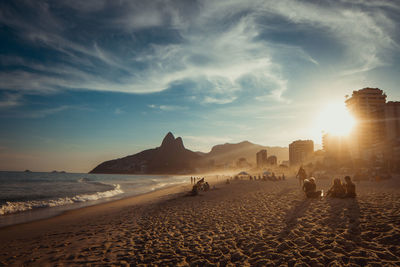 People on beach against sky during sunset