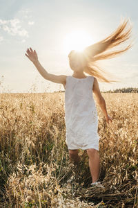 Woman with arms raised on field against sky