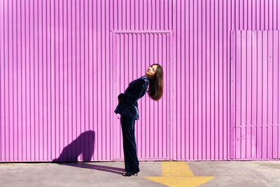 Side view of man standing against yellow wall