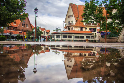 Reflection of buildings seen in puddle on street