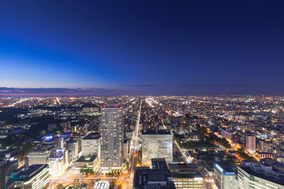 High angle view of illuminated cityscape against blue sky