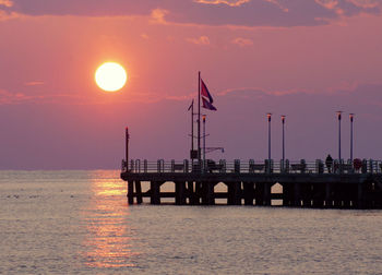 Silhouette pier over sea against sky during sunset