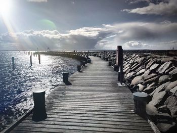 Wooden pier over sea against sky