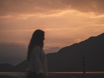 Woman standing on mountain against sky during sunset