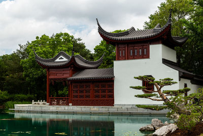 Traditional building by lake against sky