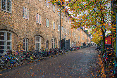 Many parked bicycles on the street near old three-story houses on an island in copenhagen, denmark