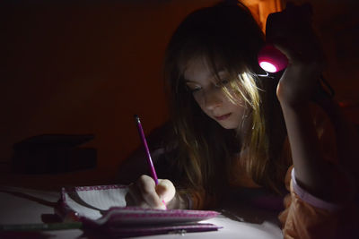 Close-up of girl writing in paper on table at home