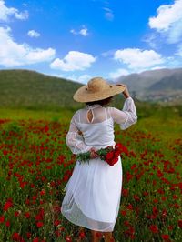 Midsection of woman standing by flowers on field