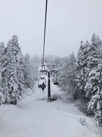 Overhead cable car on snow covered land against sky